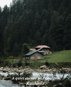 a house sitting on top of a lush green hillside next to a river and forest