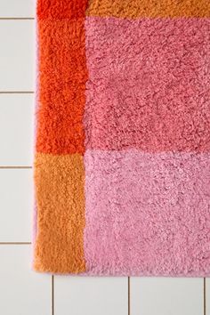 an orange and pink rug is on the wall next to a white tiled bathroom floor