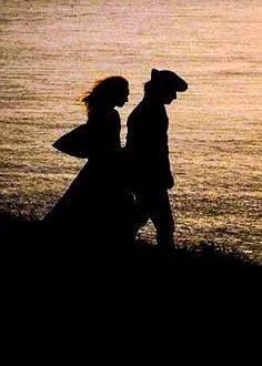 two people walking on the beach at sunset