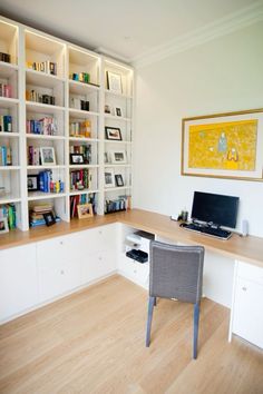 a desk with a laptop on it in front of a book shelf filled with books