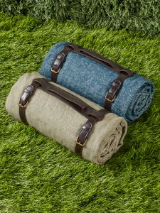 two rolled up blankets sitting on top of green grass next to each other with leather straps