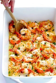 a person is spooning shrimp into a casserole