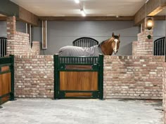 a horse that is standing in the middle of a brick wall and gated area