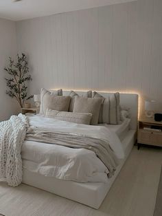 a bed with white sheets and pillows in a bedroom next to a lamp on the wall