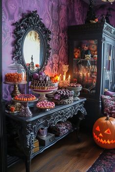 a table topped with lots of candy and pumpkins in front of a purple wall