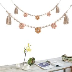 a table topped with a vase filled with flowers and tassels hanging from the ceiling