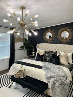 a bedroom decorated in black, white and gold with a chandelier above the bed