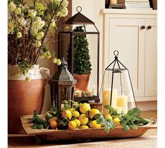 a tray filled with lemons and candles on top of a table next to potted plants