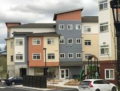 the cars are parked on the street in front of the multi - story building with many windows