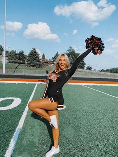 a cheerleader is posing on the football field with her pom - poms