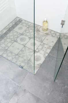 a glass shower door sitting next to a tiled floor in a room with white walls