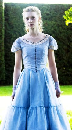 a woman in a blue dress is standing outside