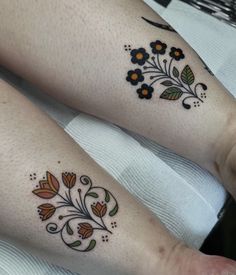 two people with tattoos on their legs sitting next to each other