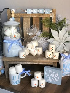 a wooden table topped with snowman candles and other decorations next to a sign that says let it snow