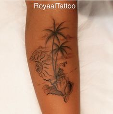 a tattoo on the leg of a woman with a palm tree and seashells