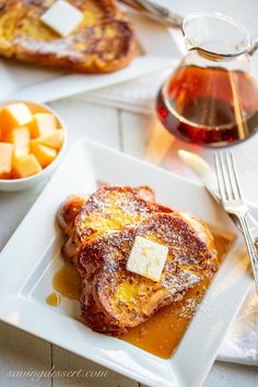 french toast with butter and syrup on a white plate next to other breakfast food items