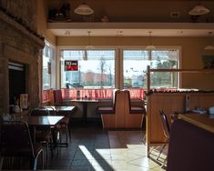 the interior of a restaurant with tables, chairs and windows looking out onto the street