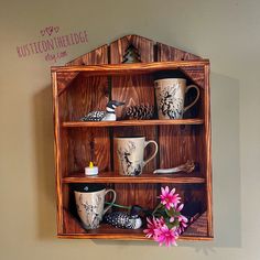 a wooden shelf with coffee mugs and flowers in it on the wall next to a sign that says rustton heritage