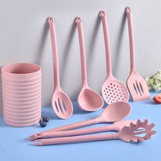 pink kitchen utensils lined up next to each other on a blue tablecloth