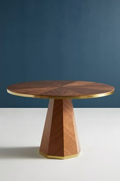 a wooden table sitting on top of a white floor next to a blue wall in the background