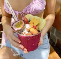 a woman is holding a fruit smoothie in her hands