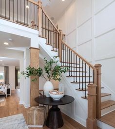 there is a vase with some flowers on the table in front of the stair case