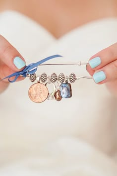 a woman holding onto a blue ribbon with charms on it and a coin attached to the end