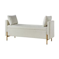 an upholstered white bench with gold legs and two pillows on the armrests