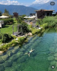 there is a man swimming in the water at this resort with mountains in the background