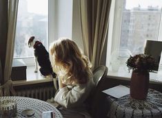 a woman sitting at a table looking out the window