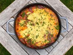 a pan filled with food sitting on top of a wooden table next to a piece of wood