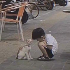 a young boy kneeling down next to a dog