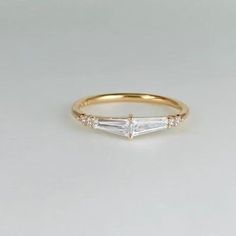 a yellow gold ring with three baguettes on the side and two diamonds in the middle