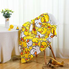 a chair covered in yellow rubber ducks on a wooden floor next to a white table