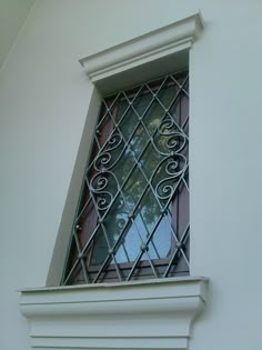 a window with iron bars on the side of it and a tree in the background