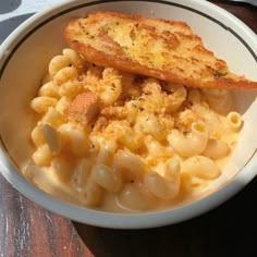 a white bowl filled with macaroni and cheese on top of a wooden table