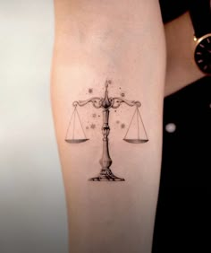 a woman's leg with a tattoo on it that has a scale and stars