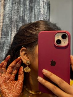 a woman is holding up her phone to take a photo with her henna tattoo