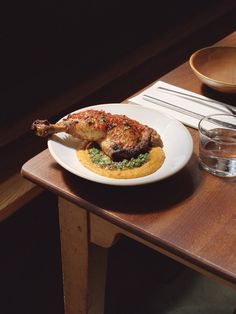 a white plate topped with food on top of a wooden table next to a glass of water