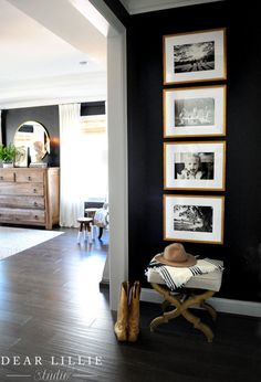 a living room with black walls and pictures hanging on the wall, along with wooden flooring