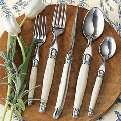 four forks, two spoons and one knife on a wooden plate with blue flowers