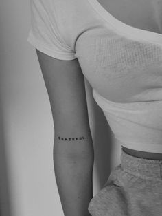 a woman's arm with the word grateful tattooed on her left side ribcage