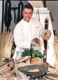 a man standing in front of a table filled with bread and other foods on it