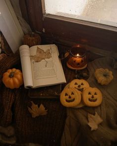 an open book sitting on top of a table next to pumpkins and other decorations