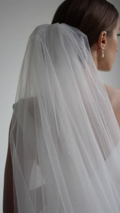 a woman wearing a wedding veil with pearls on the back of her head and shoulder