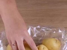 a person picking up some lemons from a plastic bag on a wooden counter top