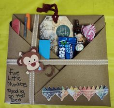 an envelope with some items in it on a yellow tableclothed surface and the message live little monkeys reading on the bottom