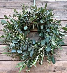 a wreath made out of green leaves and branches on a wooden surface with the word love written below it