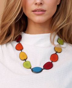 a woman with blonde hair wearing a white shirt and multicolored beads on her necklace