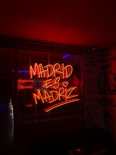 a neon sign that says madrid e & ampre in red and blue lights on the wall